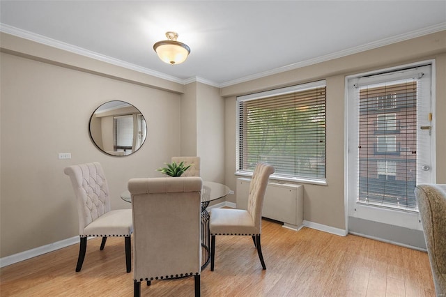 dining room featuring light wood-style floors, baseboards, and ornamental molding
