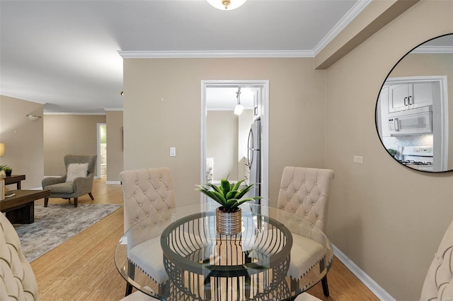 dining space featuring baseboards, ornamental molding, and wood finished floors