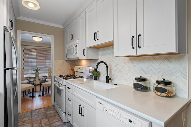 kitchen featuring backsplash, crown molding, a sink, light countertops, and white appliances