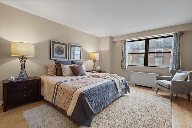 bedroom with radiator heating unit, baseboards, and wood finished floors