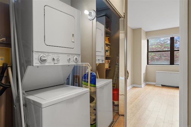 washroom featuring light wood-style floors, stacked washer and clothes dryer, baseboards, and laundry area