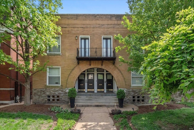 exterior space with french doors, brick siding, and a balcony