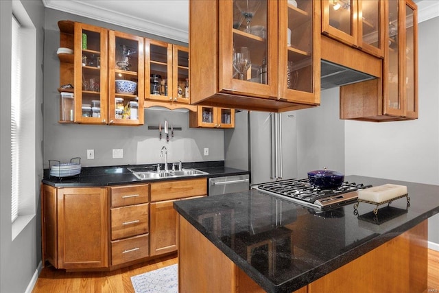 kitchen with brown cabinetry, ornamental molding, glass insert cabinets, a sink, and light wood finished floors