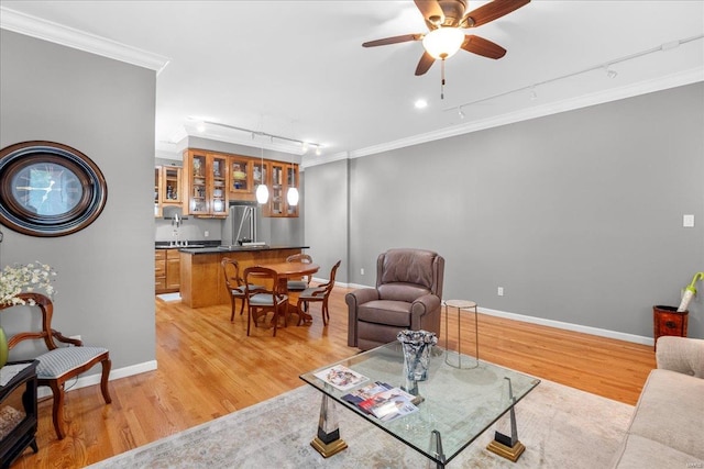 living room with track lighting, ornamental molding, and light wood-style floors