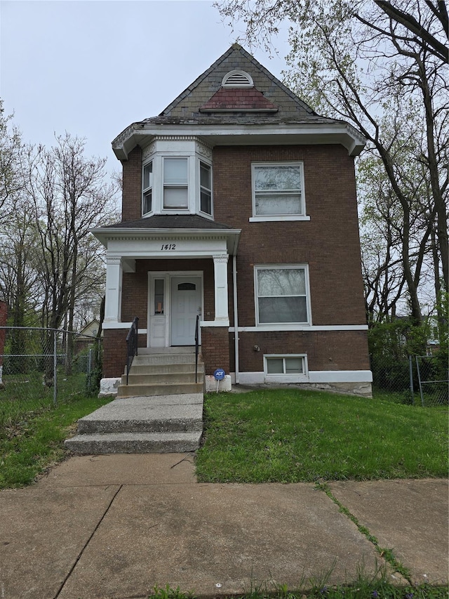 view of front of house with brick siding, fence, and a front lawn