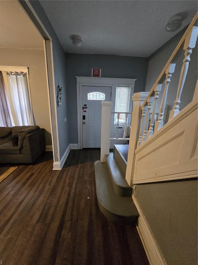foyer featuring stairway, a textured ceiling, dark wood-type flooring, and baseboards