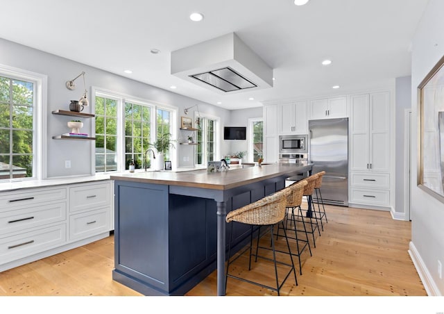kitchen featuring built in appliances, open shelves, butcher block countertops, and white cabinetry