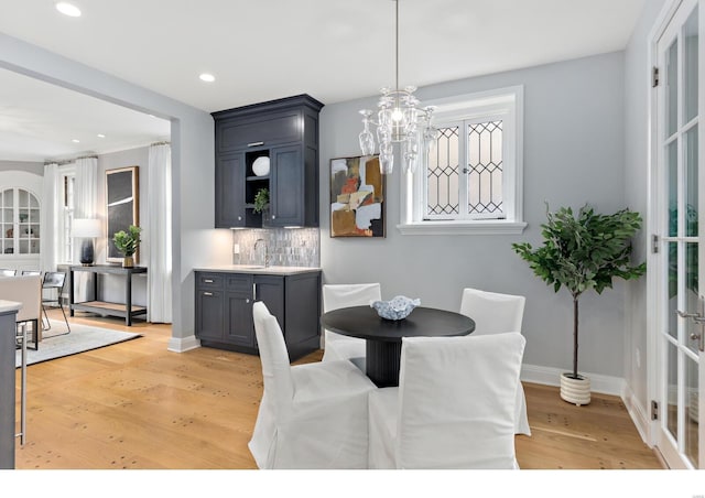 dining space with recessed lighting, a notable chandelier, baseboards, and light wood-style floors