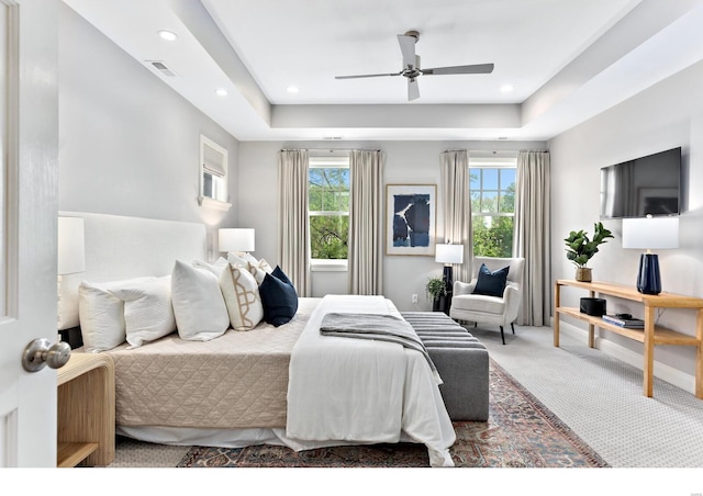 bedroom with visible vents, a raised ceiling, multiple windows, and carpet