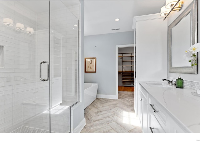full bath featuring a shower stall, a soaking tub, baseboards, recessed lighting, and vanity
