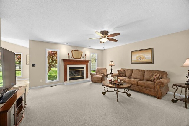 living room with plenty of natural light, a ceiling fan, and light colored carpet