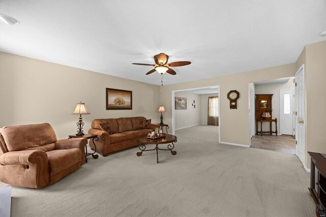 living area with carpet, baseboards, and ceiling fan