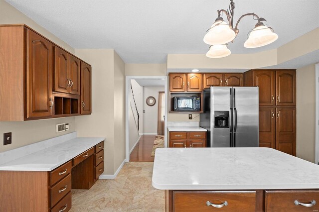 kitchen with brown cabinets, light countertops, black microwave, baseboards, and stainless steel fridge