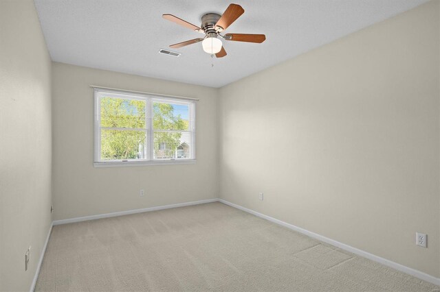 empty room with baseboards, a ceiling fan, visible vents, and light colored carpet