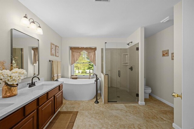 full bath with a sink, double vanity, a freestanding bath, toilet, and a shower stall