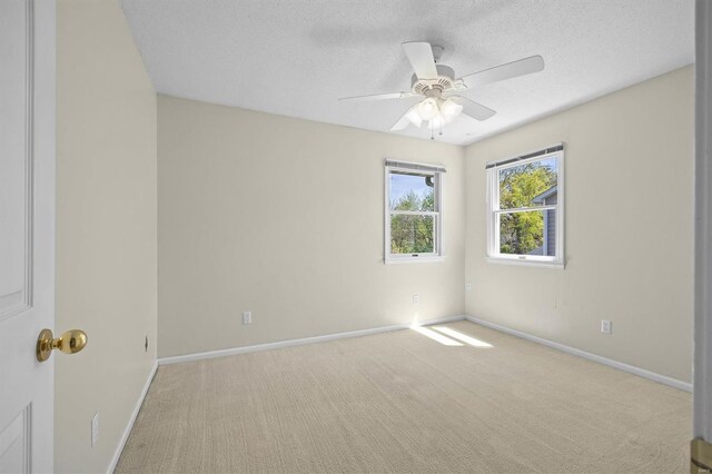 empty room with carpet floors, a textured ceiling, a ceiling fan, and baseboards