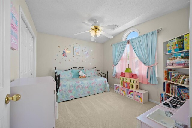 carpeted bedroom with baseboards, a ceiling fan, a textured ceiling, and a closet