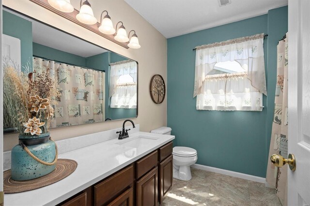 bathroom featuring toilet, vanity, and baseboards