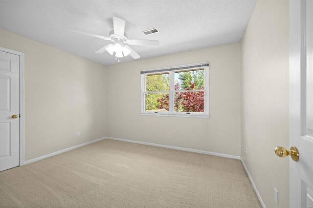 spare room featuring ceiling fan, light carpet, visible vents, and baseboards