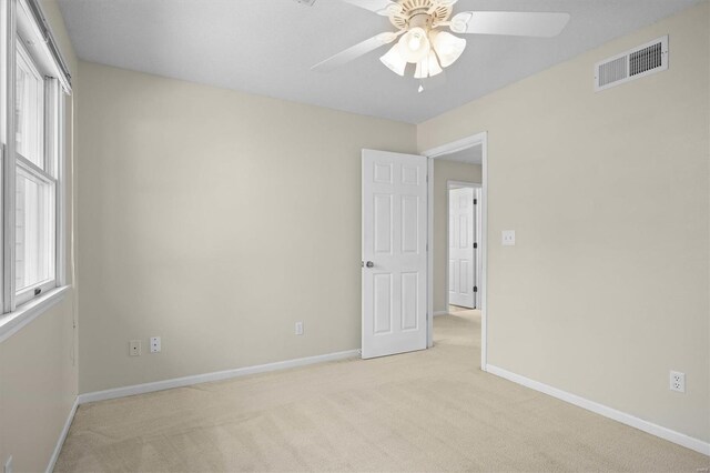 unfurnished room with ceiling fan, light carpet, visible vents, and baseboards