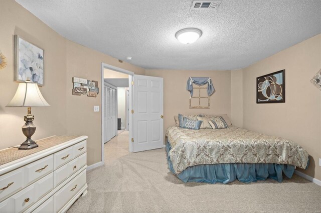 bedroom featuring light carpet, baseboards, visible vents, and a textured ceiling