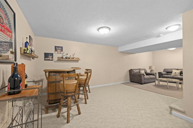 dining area featuring baseboards, carpet flooring, a textured ceiling, and a bar