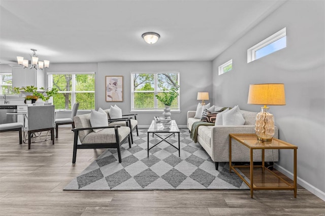 living area featuring a chandelier, baseboards, and wood finished floors