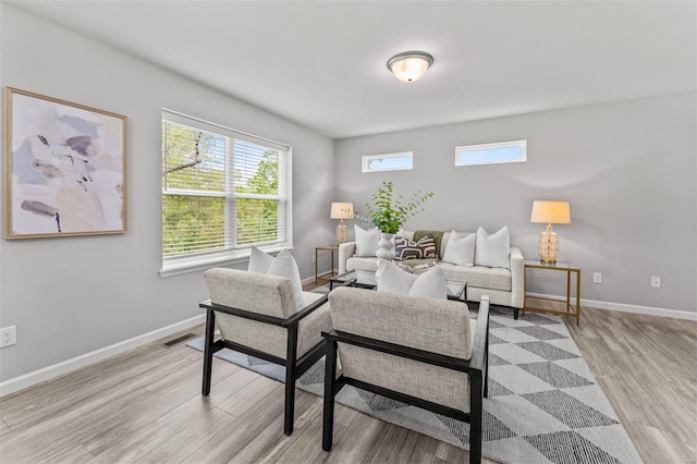 living area featuring plenty of natural light, visible vents, light wood-style flooring, and baseboards