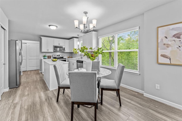 dining area featuring an inviting chandelier, light wood-style flooring, and baseboards