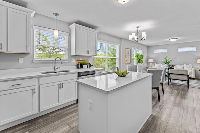 kitchen featuring an inviting chandelier, a sink, wood finished floors, light countertops, and white cabinets
