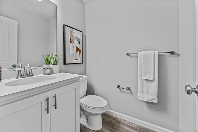 bathroom with vanity, toilet, baseboards, and wood finished floors