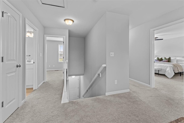 hall with carpet floors, baseboards, and an upstairs landing