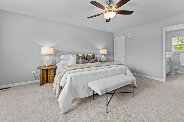 bedroom with baseboards, ensuite bath, ceiling fan, visible vents, and light carpet