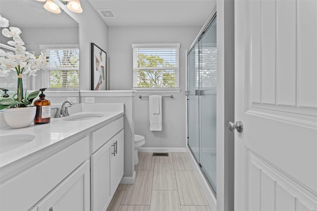 full bath featuring double vanity, toilet, a stall shower, a sink, and visible vents