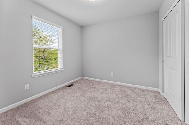 unfurnished bedroom featuring carpet, visible vents, baseboards, and a closet
