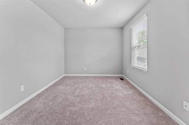 empty room featuring visible vents, baseboards, and carpet floors