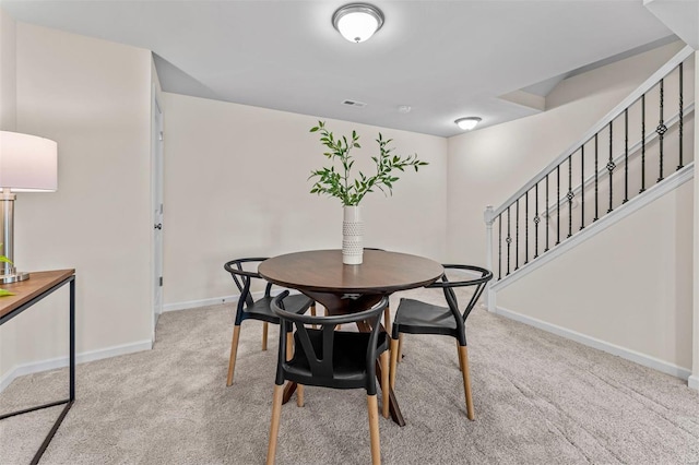 carpeted dining room featuring visible vents, baseboards, and stairs