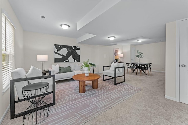living area with baseboards, light carpet, and visible vents