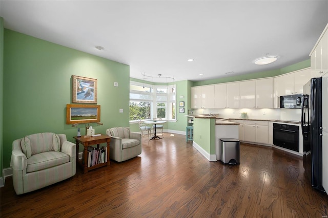 kitchen featuring a kitchen island, baseboards, dark wood-style floors, white cabinets, and black appliances