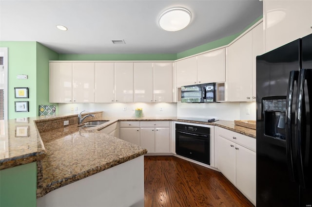 kitchen featuring visible vents, a sink, white cabinets, black appliances, and dark wood-type flooring
