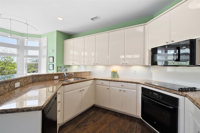 kitchen with visible vents, dark wood-type flooring, white cabinets, a sink, and black appliances