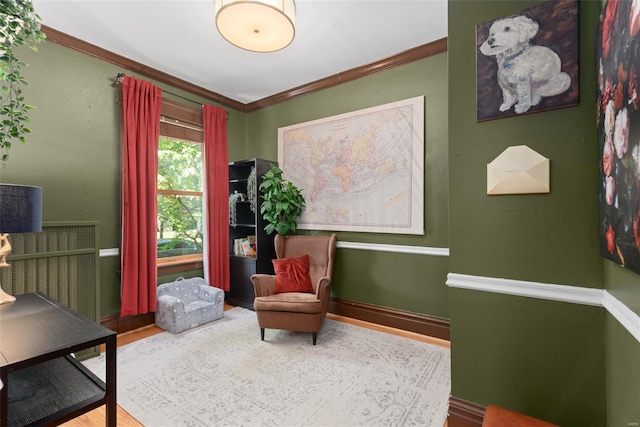 sitting room with crown molding, baseboards, and wood finished floors
