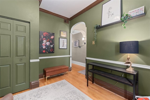 sitting room with visible vents, arched walkways, wood finished floors, and ornamental molding
