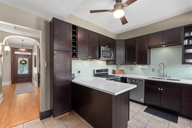 kitchen featuring open shelves, appliances with stainless steel finishes, a sink, light countertops, and a peninsula