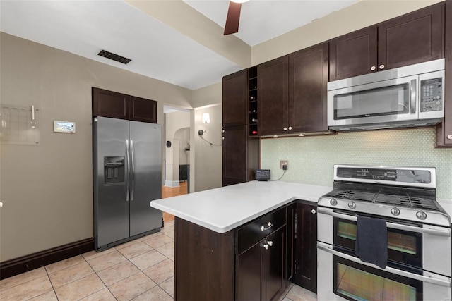 kitchen featuring tasteful backsplash, dark brown cabinets, light countertops, a peninsula, and stainless steel appliances