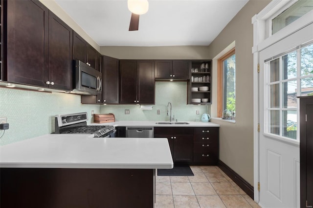 kitchen featuring decorative backsplash, dark brown cabinets, light countertops, a sink, and appliances with stainless steel finishes