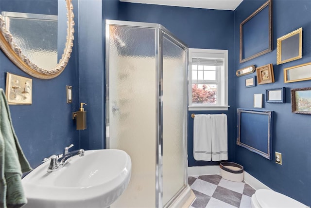 full bathroom featuring a sink, baseboards, a shower stall, and toilet