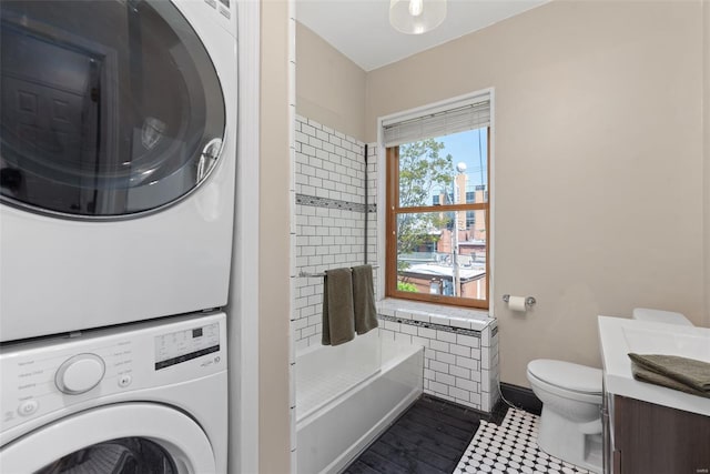 interior space featuring stacked washer / drying machine, vanity, toilet, baseboards, and wood finished floors
