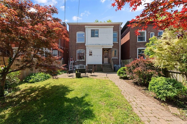 rear view of house with central AC unit, fence, a yard, and entry steps