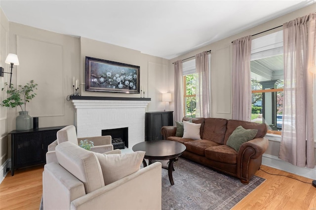 living room featuring a brick fireplace and wood finished floors